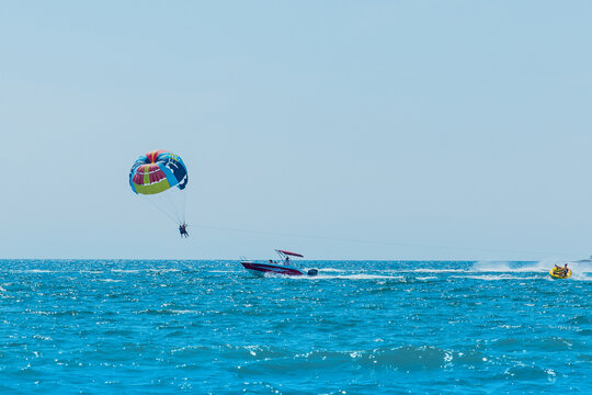 Ukraine, Iron Port - August 27, 2020: Extreme sports and exciting rest. Tourists fly on parashute in the blue sky above the sea and the horizon line background