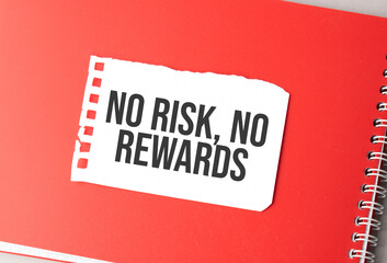 The word no risk, no rewards on torn paper on red notepad,.