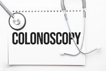 Grey stethoscope and paper plate with a sheet of white paper with text Colonoscopy light blue...