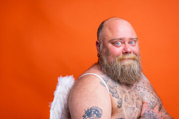 Fat happy man with beard ,tattoos and wings acts like an angel