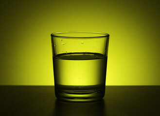 A glass with water at yellow background	