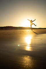 person jumping on the beach at sunset