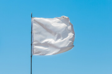 White flag sign and symbol of goodness and truce on blue sky background
