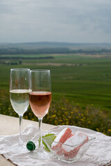Symbols of Reims, white and rose brut champagne wine and rose biscuits and view on green pinot noir grand cru vineyards of famous champagne houses in Montagne de Reims near Verzenay, Champagne, France