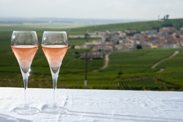Tasting of rose brut champagne wine with view on green pinot noir grand cru vineyards of famous champagne houses in Montagne de Reims near Verzenay, Champagne, France