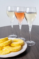 Tasting of white and rose champagne sparkling wine from flute glasses, pairing with fresh ripe pineapple