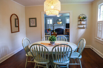A small dining room with a statement rattan lighting ficture and a painted blue dining room table