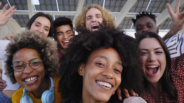 Young African American girl takes a cell phone photo with her multiracial group of friends. Concept of friendship, having fun.