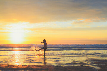 A girl stands at the shore of the ocean school age child playing and splashing sea water at the beach