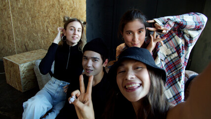 Four teens sitting on a sofa and waving to the camera to make selfie