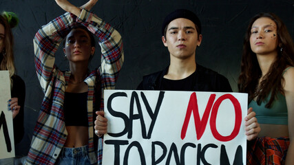 Fototapeta na wymiar Young girls and a guy holding banners for awareness campaign against racial discrimination