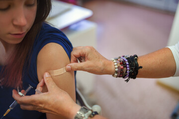 A young woman after a vaccination looks at the patch that has just been applied over her injection site.