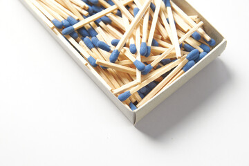 Close up of matchbox on a white background, pile of phosphorus blue head matchsticks isolated. Used for a barbecue ignite or kitchen household