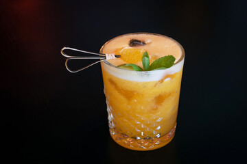 Beautiful yellow citrus cocktail with ice and decoration with an orange piece and mint leaves