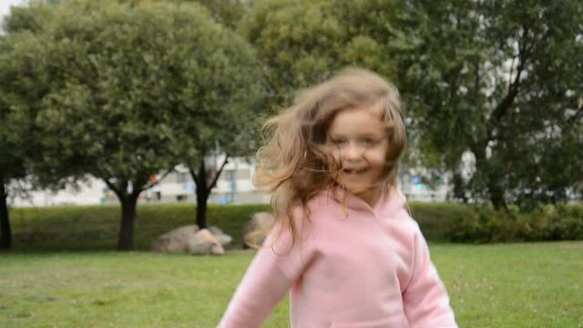 happy little girl jumping and rejoicing in the park on the grass