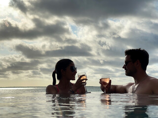 Lovely couple celebrating live in a natural pool with oceanfront panoramic view of the sunset in a...