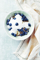 Bowl of granola with yogurt and bilberries. Concept for a tasty and healthy meal. Bright wooden background. Top view. Copy space.	