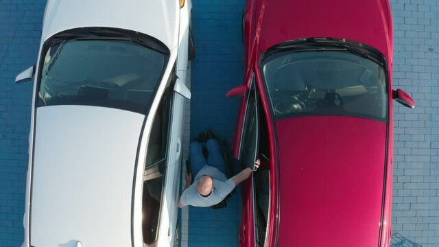 Young handicapped driver getting in red car from wheelchair