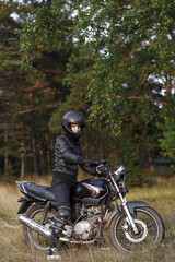 Obraz na płótnie Canvas biker girl in black clothes and black helmet on a motorcycle