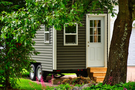 Tiny home on wheels framed by trees and flowers