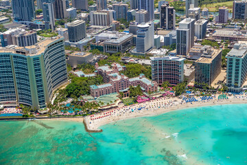 Aerial view of Waikiki Beach, Oahu, Hawaii. Turquoise blue water bordered by golden sandy beaches and hotels.  The pink Royal Hawaiian Hotel is prominent in scene.