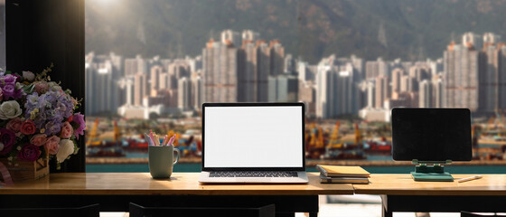 Mockup laptop computer with blank white screen on workplace, cargo port and building background