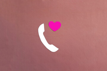 The handset is white, with a heart on a pink background. Love, communication, correspondence of a couple, transfer of information.