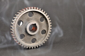 Engine parts. Metal cogwheel on a dark background. Spare parts.