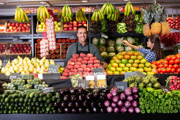 Portrait of young male in apron selling fruits and vegetables in shop