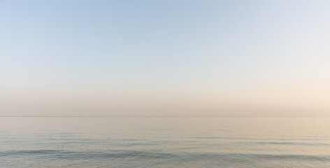Fototapeta na wymiar Calm evening sea surface with clear blue sky. Evening seascape. 