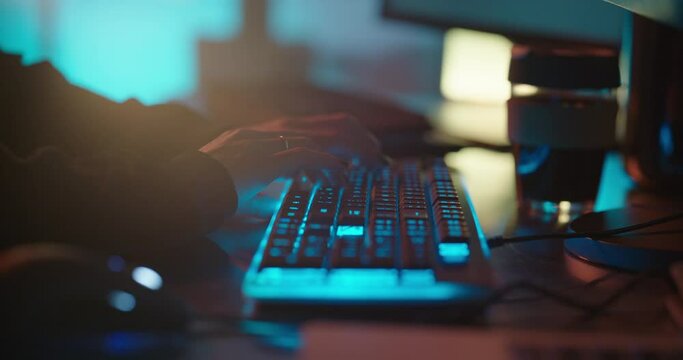 computer hands typing on keyboard programmer coding hacking data on internet cyber crime information hack by anonymous hacker using rgb gaming keyboard with blue backlight