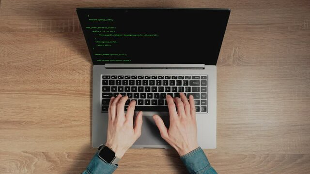 Timelapse of man hands are typing commands of a laptop keyboard. A man is writing a program. The developer is coding. Code on the laptop screen. Concept of programming and development web.