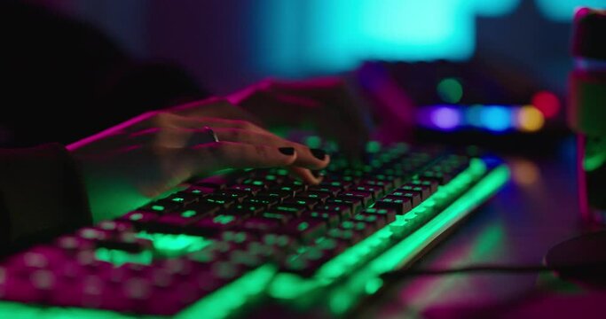 computer hands typing on keyboard hacking data on internet cyber crime information hack by anonymous hacker using rgb gaming keyboard with green backlight