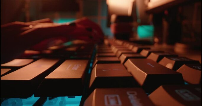 macro hands typing on keyboard computer programmer coding software using keyboard with blue backlight anonymous person hacking at night