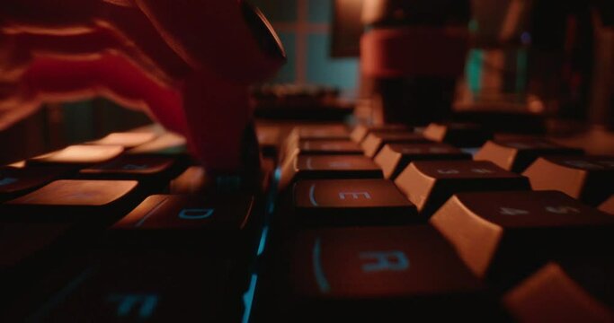 macro hands typing on keyboard computer programmer coding software using keyboard with blue backlight anonymous person hacking at night