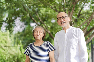 笑顔で公園を散歩する高齢者の夫婦