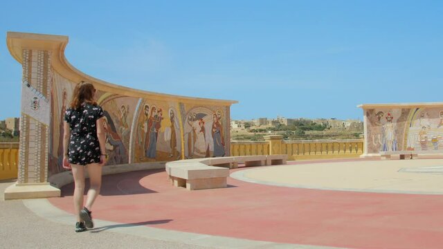 Female Tourist Walking Towards Frescos, Mural Painting In Basilica of the National Shrine of the Blessed Virgin of Ta' Pinu In Gharb, Malta. - wide shot