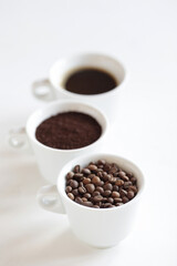 Obraz premium Assorted coffee in white cups, coffee beans, ground and black brewed. White background, copy space.