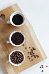 Assorted coffee in white cups, coffee beans, ground and black brewed. White background, copy space. Concept