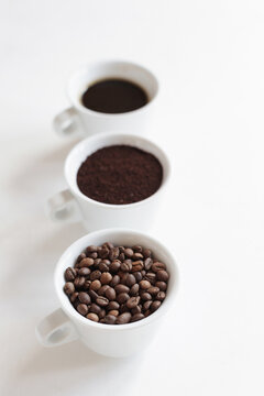 Assorted coffee in white cups, coffee beans, ground and black brewed. White background, copy space. Concept