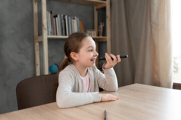 Voice assistant. Happy girl dictates text using microphone of smartphone or mobile phone. student...