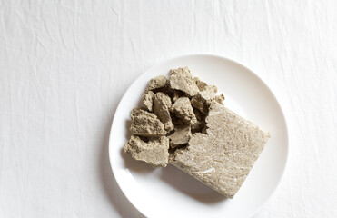 White plate with halvah on a light background. Copy space, minimalistic background.