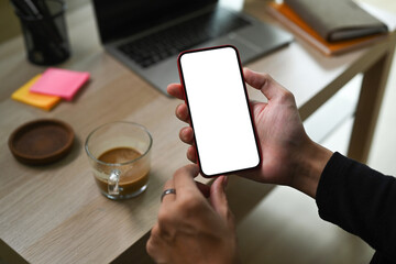 Close up view man holding smart phone while sitting on sofa in living room.