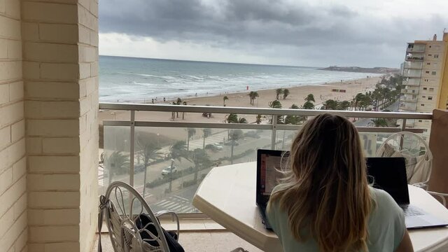 Young couple working from home at the beach in a rainy day.