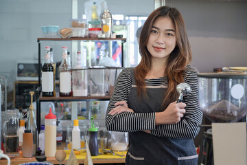 Portrait of beautiful barista holding portafilter and smiling to camera while standing in a cafe.