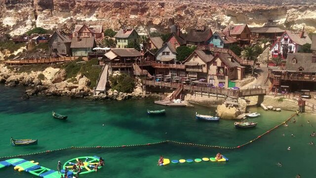 Film set from the 1980 musical 'Popeye', now a theme park in Mellieha, Malta‎. Aerial view of Popeye Village on a sunny day. People are swiming and having fun in the water.