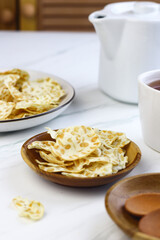 Keripik Tempe or Tempeh Crackers or tempeh chips on ceramic bowl with cup of tea. Tea and snack time. Selective focus, copy space. Indonesian snack.
