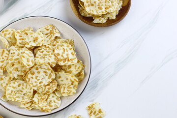 Keripik Tempe or Tempeh Crackers or tempeh chips on ceramic bowl with cup of tea. Tea and snack time. Selective focus, copy space. Indonesian snack.