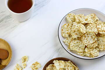 Keripik Tempe or Tempeh Crackers or tempeh chips on ceramic bowl with cup of tea. Tea and snack time. Selective focus, copy space. Indonesian snack.