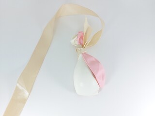 Some white and pink uninflated balloons wrapped with ribbon.